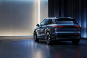 En umærket stor elektrisk SUV set skråt bagfra i et mørkeblåt udstillingsrum.